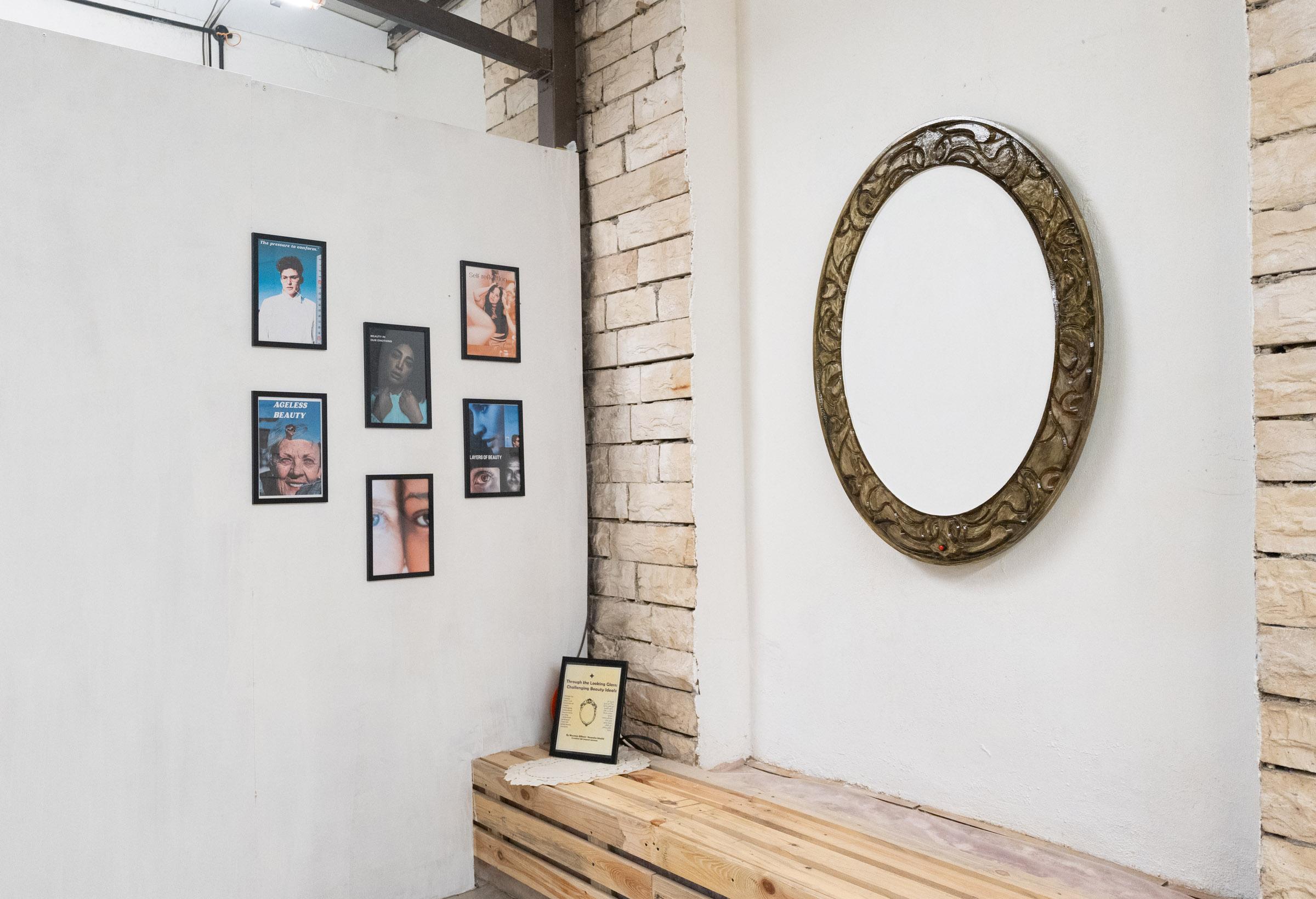 Wide shot of installation with large oblong mirror-like frame hanging on the wall; adjacent are six framed images of individuals.