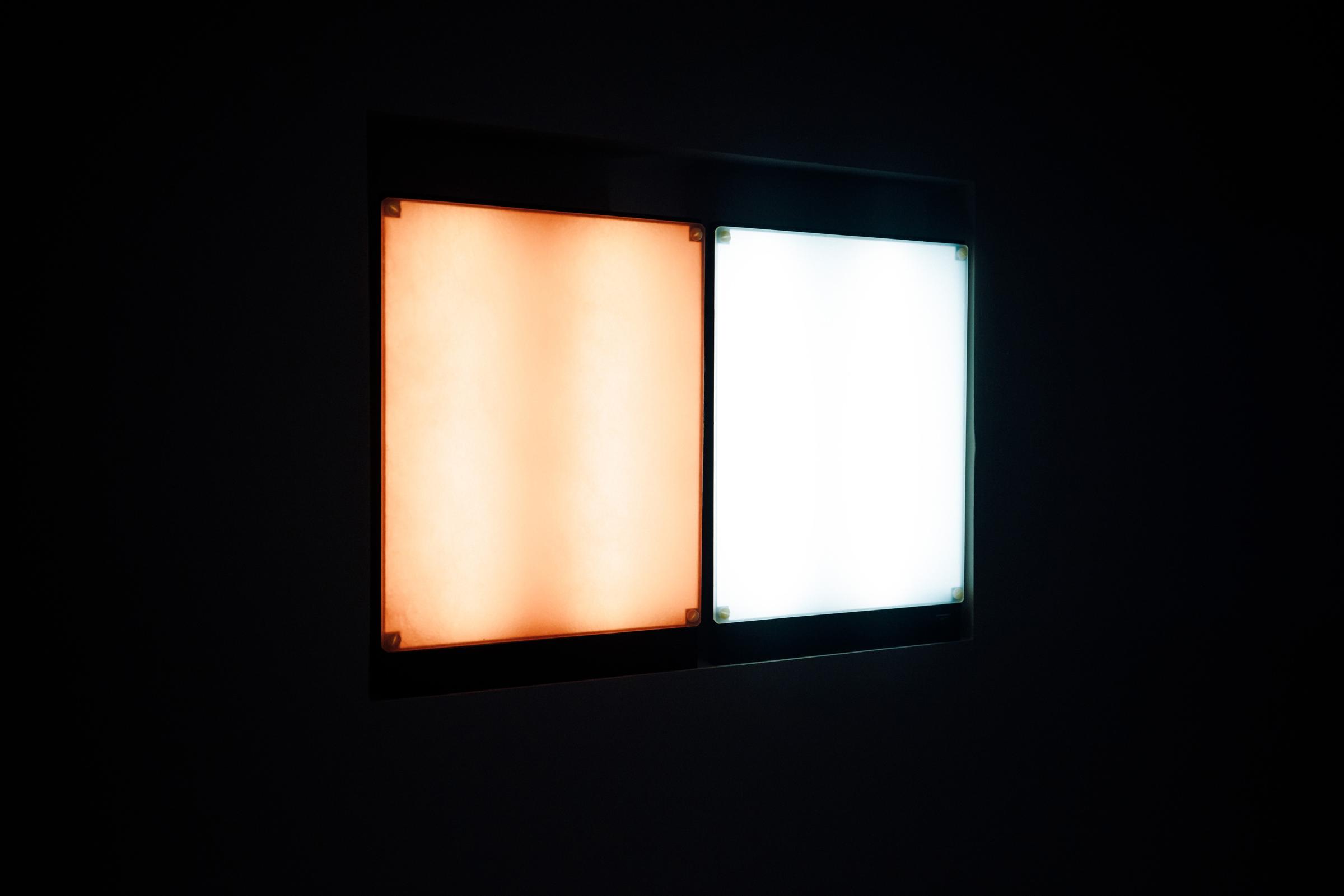 A light box against a dark background. One half is emitting a bright amber glow resembling dawn’s warmer orange light. The other half is a cool white light. 