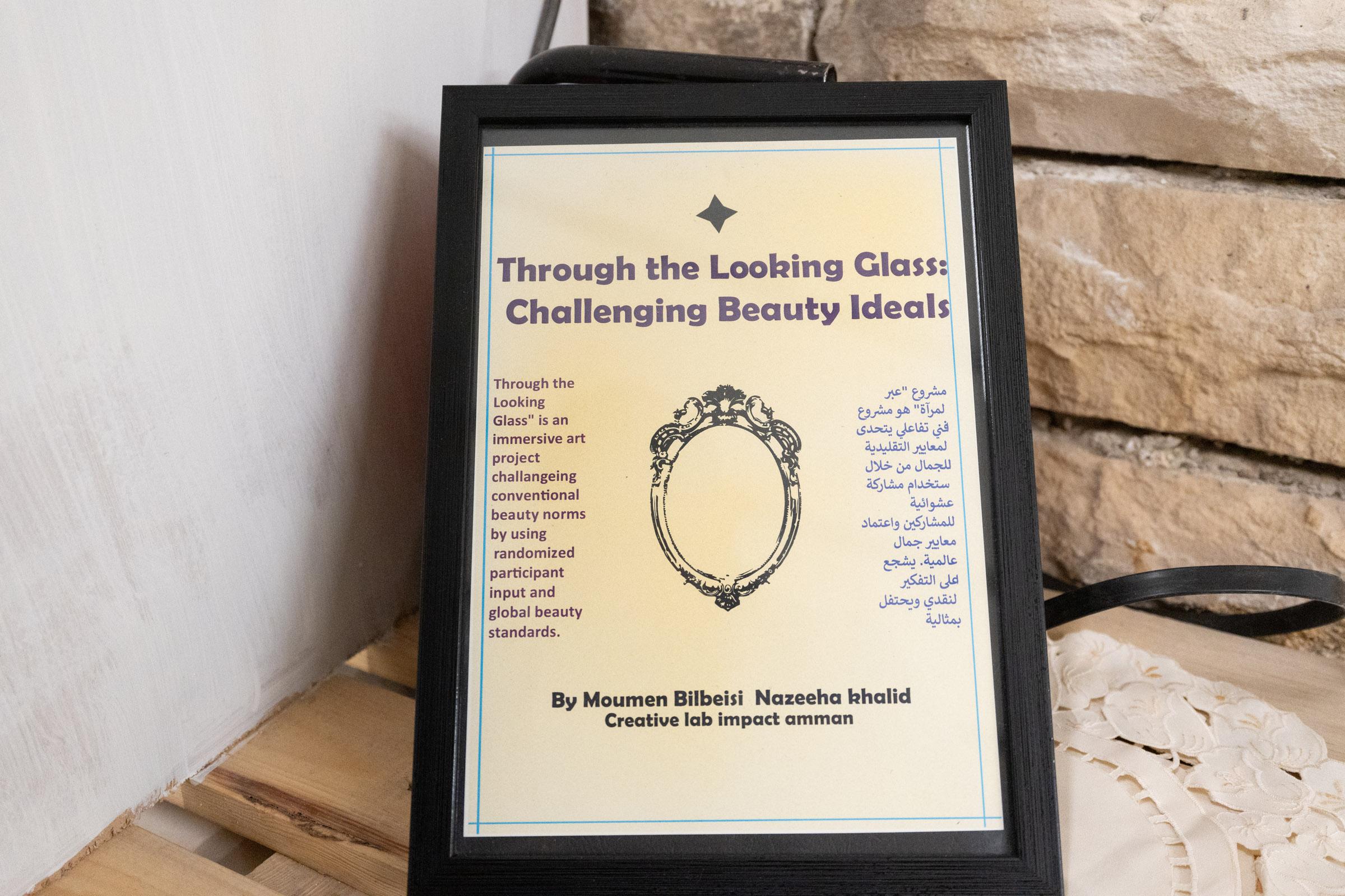 Sign on a golden prismatic background reading “Through the Looking Glass: Challenging Beauty Ideals” with an image of an ornate mirror and text in both English and Arabic.