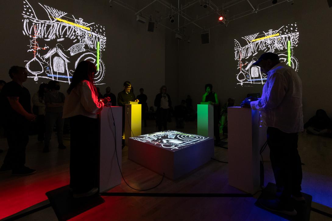 People gathered at four podiums around a glowing light projection.