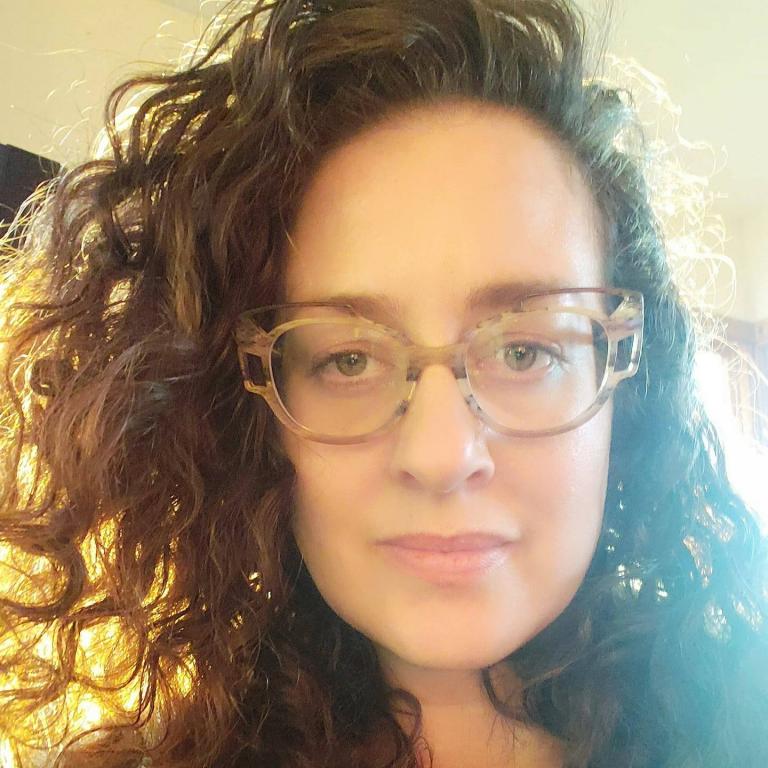 light skinned woman with curly hair and glasses