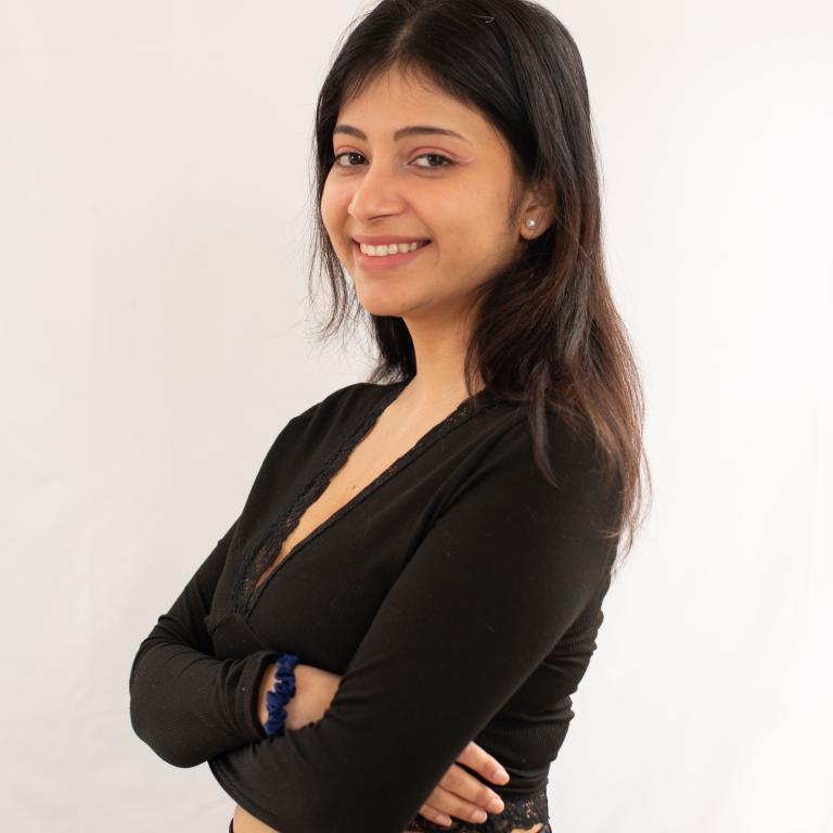 A picture of Sunidhi Naik in a black top and black pants showing the front and side profile, smiling.